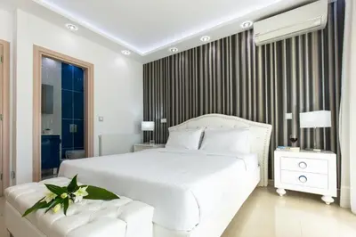 a white bedroom with a large white bed and a window at Larimar Luxury Sea View Villa in Kissamos
