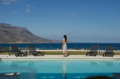 a woman is standing next to a swimming pool at Larimar Luxury Sea View Villa in Kissamos