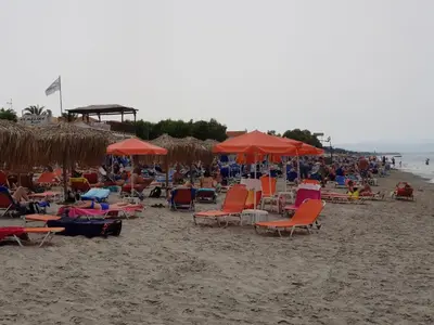 a beach with chairs and umbrellas and a crowd of people at Platania's Horizon in Plataniás