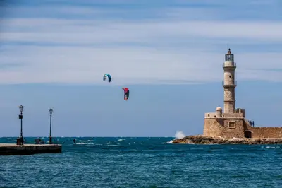 a lighthouse on the ocean with people kite surfing at Koum Kapi Boutique Apartments in Chania Town
