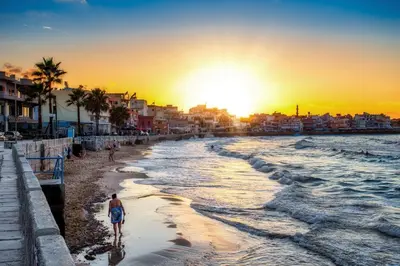 a man walking on the beach at sunset at Koum Kapi Boutique Apartments in Chania Town