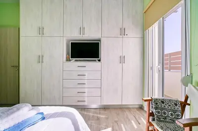 a bedroom with white cabinets and a television in it at Seaside House in Kissamos