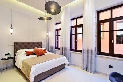 a bedroom with a bed and two windows at Neorion Living in Chania Town