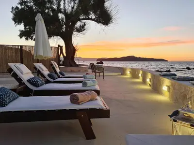 a row of chaise lounges on the beach at sunset at Seastar seafront villa in Kalamaki Chanion