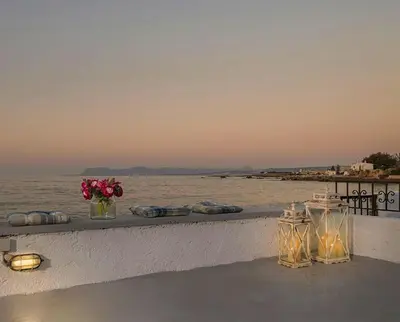 a table with a vase of flowers next to the water at Seastar seafront villa in Kalamaki Chanion