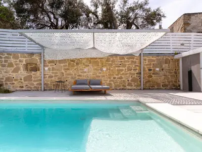 a swimming pool with a bench next to a stone wall at Villa Evrithea in Kalleryianá