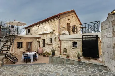 a stone house with a patio with a table at Traditional Stone House Rafael in Tzitzifés