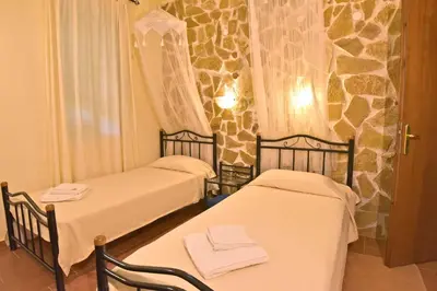 two beds in a room with a stone wall at Olive Farm in Agia Marina Nea Kydonias