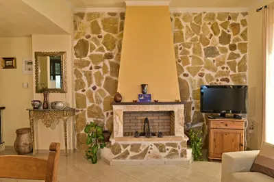 a living room with a stone fireplace and a tv at Olive Farm in Agia Marina Nea Kydonias