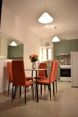 a kitchen with a table with orange chairs and a refrigerator at Iris Apartment in Chania Town