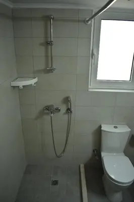 a bathroom with a shower with a toilet and a window at Iris Apartment in Chania Town