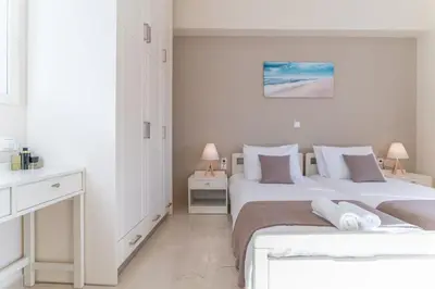 a white bedroom with two beds and two lamps at Helios Residence in Chania Town
