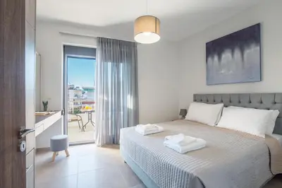 a white bedroom with a bed and a balcony at Casa Ntore Luxury Apartments in Chania Town