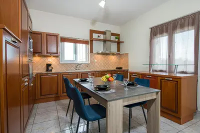 a kitchen with a table with blue chairs and a tableablish at Ifigeneia's Lavish Escape with Private Hot Tub in Kalathas