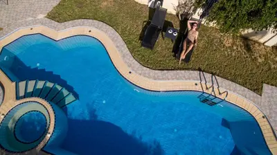 a man is standing next to a large swimming pool at Ifigeneia's Lavish Escape with Private Hot Tub in Kalathas