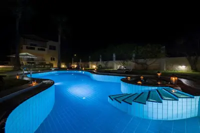 a swimming pool lit up at night at Ifigeneia's Lavish Escape with Private Hot Tub in Kalathas