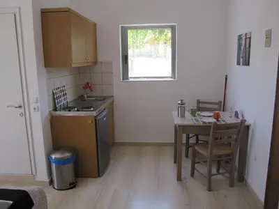 a kitchen with a table and a sink and a table and chair at Lion-Suites in Kalyves