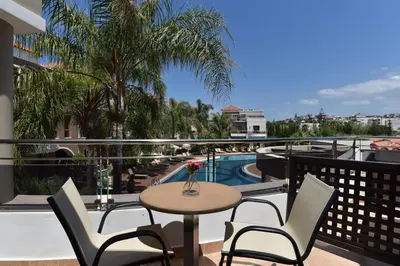 a balcony with a table and chairs and a pool at Okeanis Golden Resort in Kato Daratso