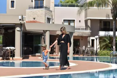 a woman and a child walking by a pool at Okeanis Golden Resort in Kato Daratso