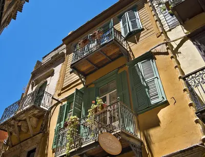 a yellow building with green shutters and balconies at Antica Casa Studios in Chania Town