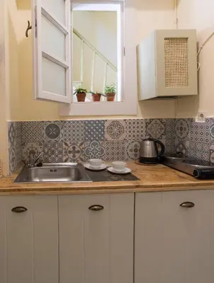 a kitchen with white cabinets and a sink at Antica Casa Studios in Chania Town