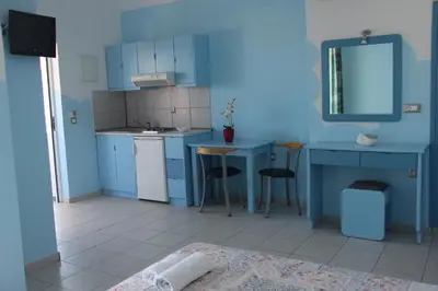 a small kitchen with blue cabinets and a table and chairs at Mastorakis Village in Agia Marina Nea Kydonias