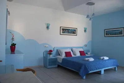 a blue bedroom with a bed with red pillows at Mastorakis Village in Agia Marina Nea Kydonias