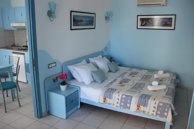 a blue bedroom with a bed and a kitchen at Mastorakis Village in Agia Marina Nea Kydonias