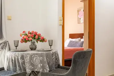a table with a vase of flowers and two chairs at Panoramio Paleochora Apartments in Palaiochóra