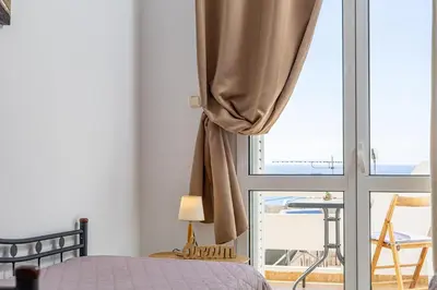 a bedroom with a bed and a sliding glass door at Panoramio Paleochora Apartments in Palaiochóra