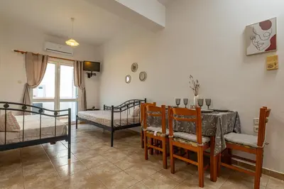 a bedroom with two beds and a table and chairs at Panoramio Paleochora Apartments in Palaiochóra