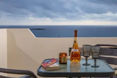 a bottle of wine and two glasses on a table at Panoramio Paleochora Apartments in Palaiochóra