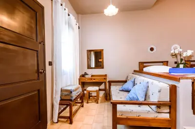 a bedroom with a bed and a desk and a door at Gregory Village Sea View in Stalos