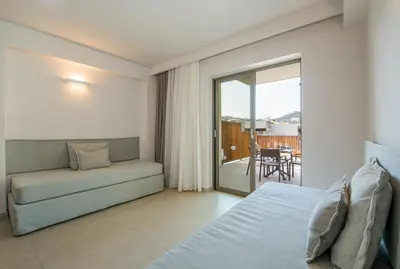 a bedroom with a bed and a couch and a balcony at Stefan Village Hotel in Agia Marina Nea Kydonias