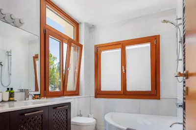 a bathroom with a tub and a toilet and windows at Angels Villa - 8-Bedroom Estate Ideal for Groups & Families by etouri in Kambánion
