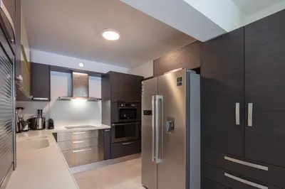a kitchen with wooden cabinets and a stainless steel refrigerator at Angels Villa - 8-Bedroom Estate Ideal for Groups & Families by etouri in Kambánion