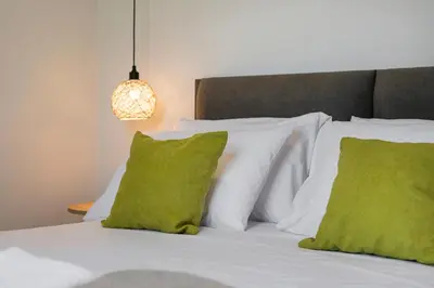 a bed with white pillows and green pillows at Aegean Breeze Luxury Apartments next to the sea in Maleme
