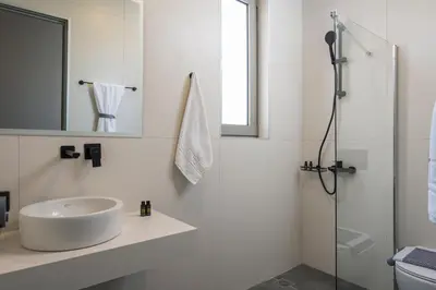 a white bathroom with a sink and a shower at Aegean Breeze Luxury Apartments next to the sea in Maleme