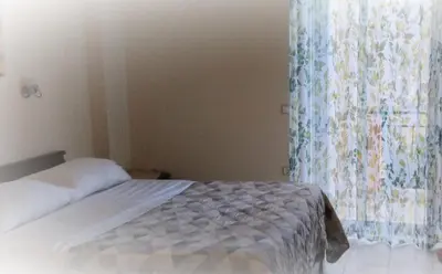 a bedroom with a bed and a window with a curtain at Riza Falasarna Apartments in Falasarna