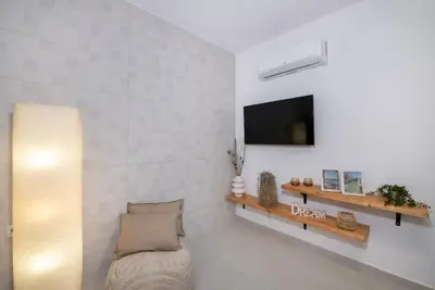 a living room with a couch and a tv on a wall at Elenas Home - Dream & Love apts w Private pool in Alikianós
