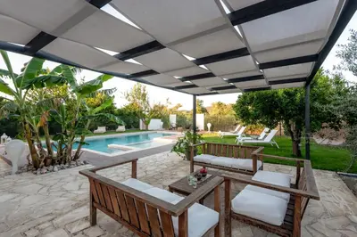 a patio with a white umbrella and chairs and a pool at Elenas Village House - Love apartment with Pool and Terrace in Alikianós