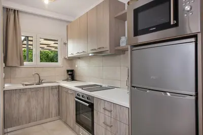 a kitchen with wooden cabinets and a white refrigerator at Elenas Village House - Love apartment with Pool and Terrace in Alikianós