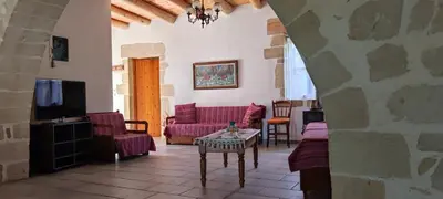 a living room with purple couches and a tv at Irene's Guest House in Frés