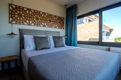 a bedroom with a bed and a large window at Amphitheatre Suites in Palaiochóra