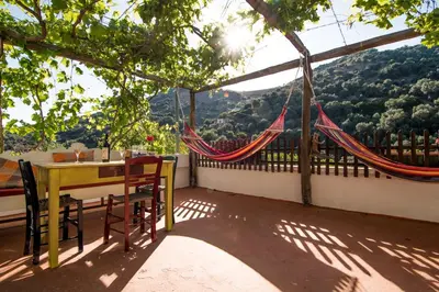 a patio with a table and chairs and a hammock at Spitia Anoi in Palaiochóra
