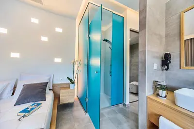 a bathroom with a bed and a shower and a sink at Lilium Luxury Suites in Agia Marina Nea Kydonias
