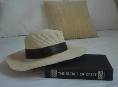 a hat and a book sitting on a bed at New Sea Escape Boutique Apt-Agii Aposto li beach in Chania Town