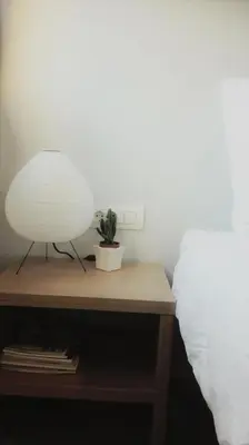 a nightstand with a plant on it next to a bed at New Sea Escape Boutique Apt-Agii Aposto li beach in Chania Town