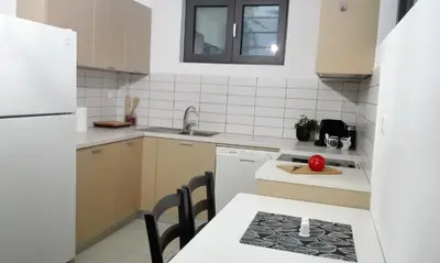 a kitchen with white appliances and a table with a apple on the counter at New Sea Escape Boutique Apt-Agii Aposto li beach in Chania Town