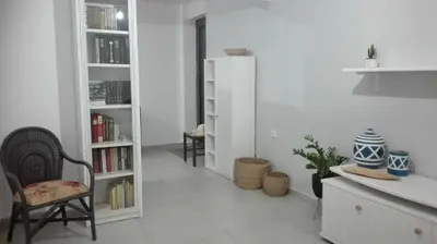 a room with a chair and a book shelf with books at New Sea Escape Boutique Apt-Agii Aposto li beach in Chania Town